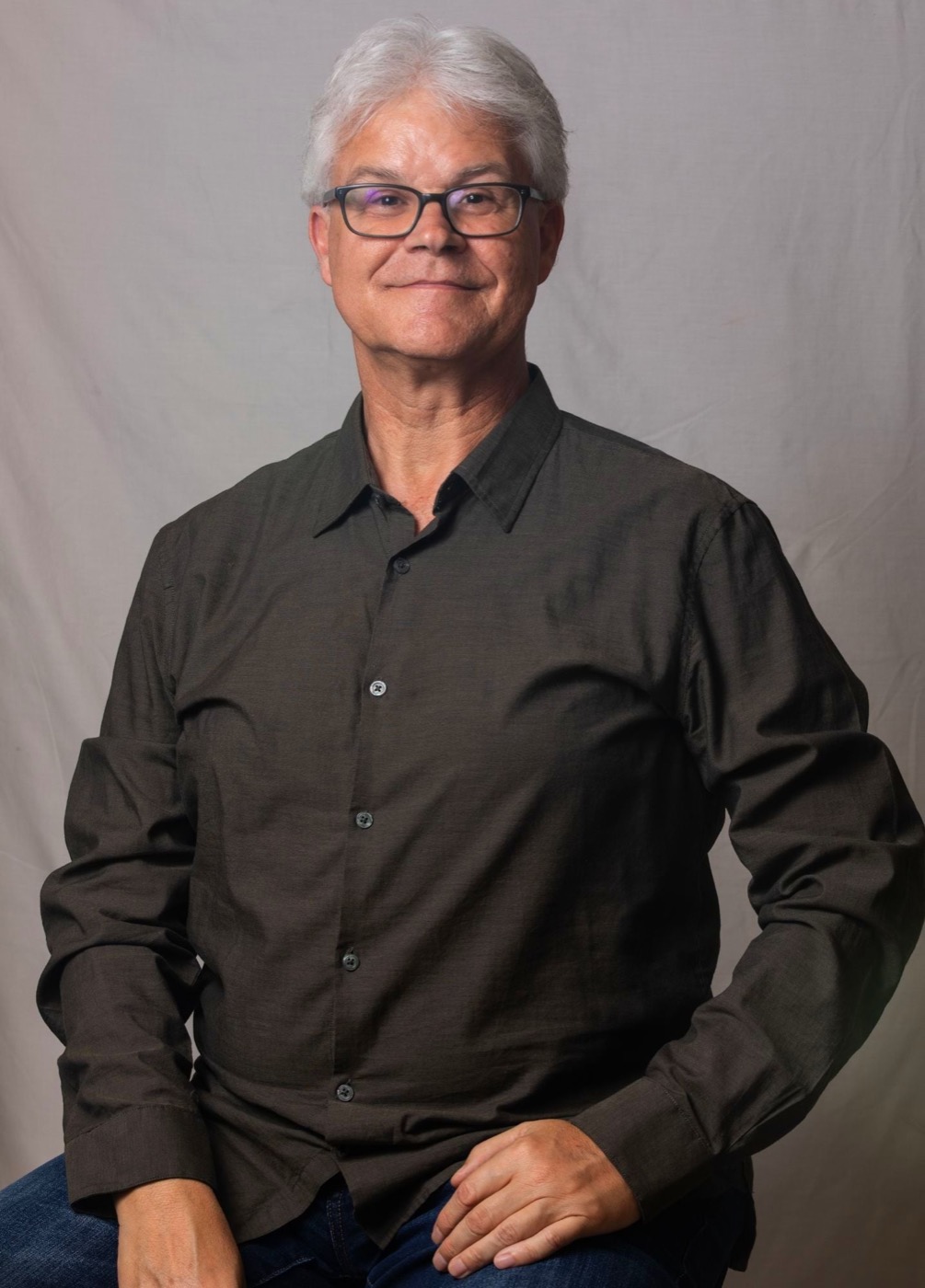 Patrick Peterhans seated in a dark olive shirt, hands resting on his knee